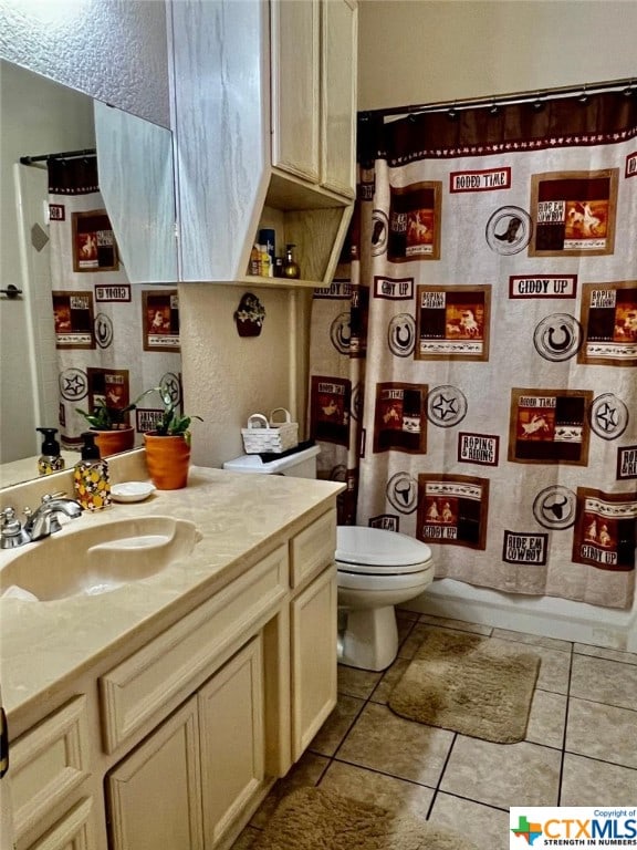 bathroom with toilet, vanity, and tile patterned floors