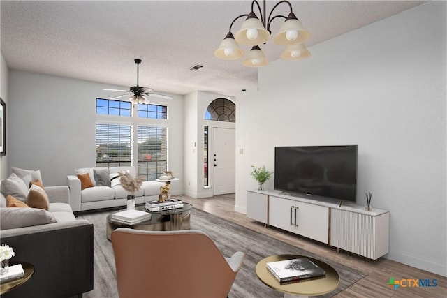 living room with hardwood / wood-style floors, ceiling fan with notable chandelier, and a textured ceiling