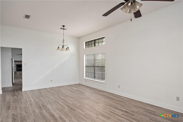 empty room with light hardwood / wood-style floors and ceiling fan with notable chandelier