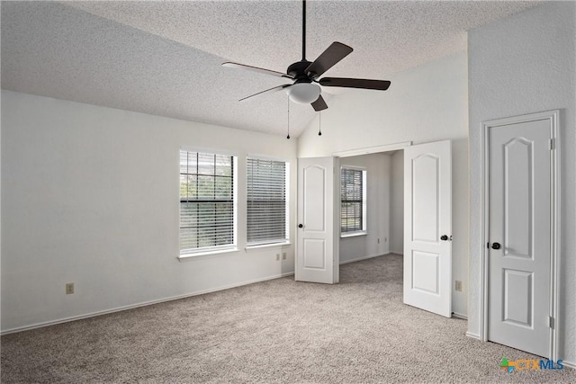 unfurnished bedroom featuring light carpet, a textured ceiling, vaulted ceiling, and ceiling fan