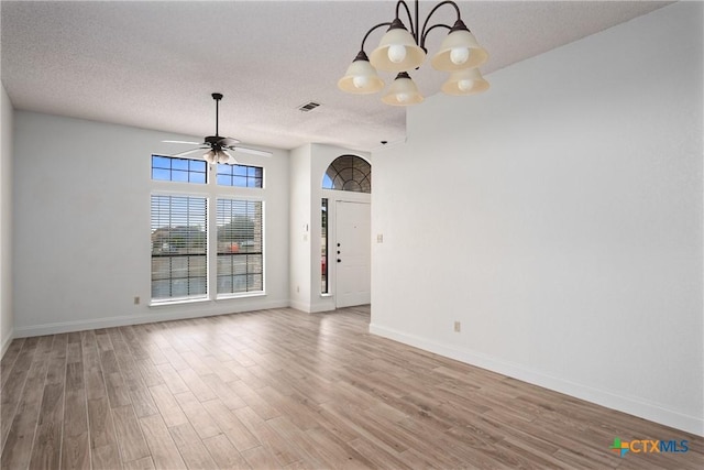 empty room with ceiling fan with notable chandelier, wood-type flooring, and a textured ceiling