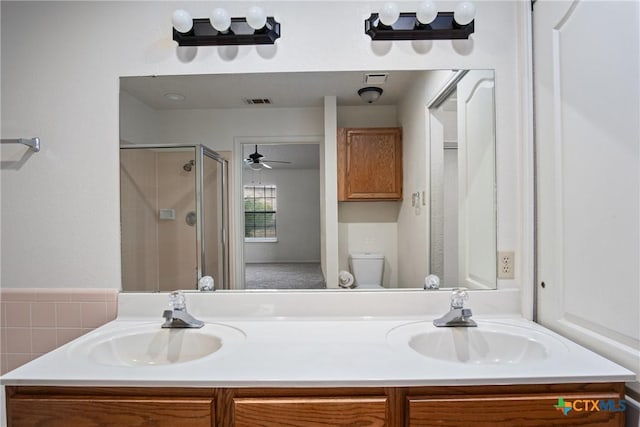 bathroom with ceiling fan, vanity, a shower with shower door, and toilet