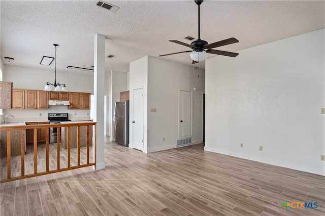 kitchen featuring ceiling fan, sink, stainless steel appliances, a textured ceiling, and light wood-type flooring