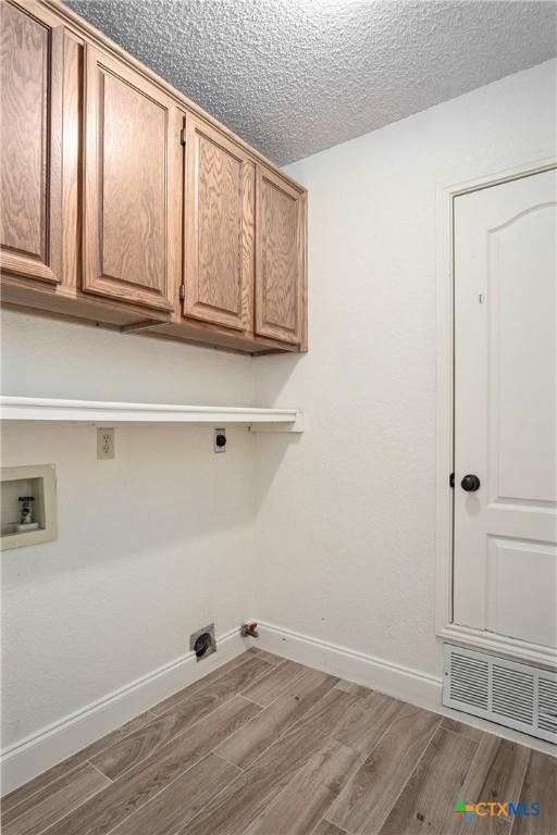 washroom featuring hardwood / wood-style flooring, hookup for an electric dryer, cabinets, and hookup for a washing machine