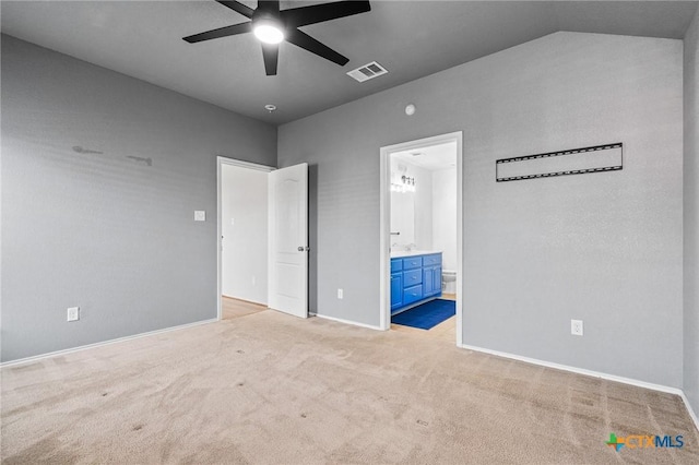 unfurnished bedroom featuring ceiling fan, vaulted ceiling, ensuite bath, and light colored carpet