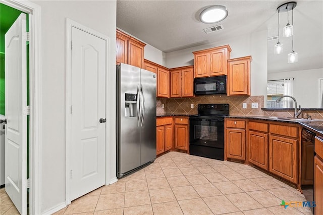 kitchen featuring sink, light tile patterned flooring, black appliances, hanging light fixtures, and decorative backsplash