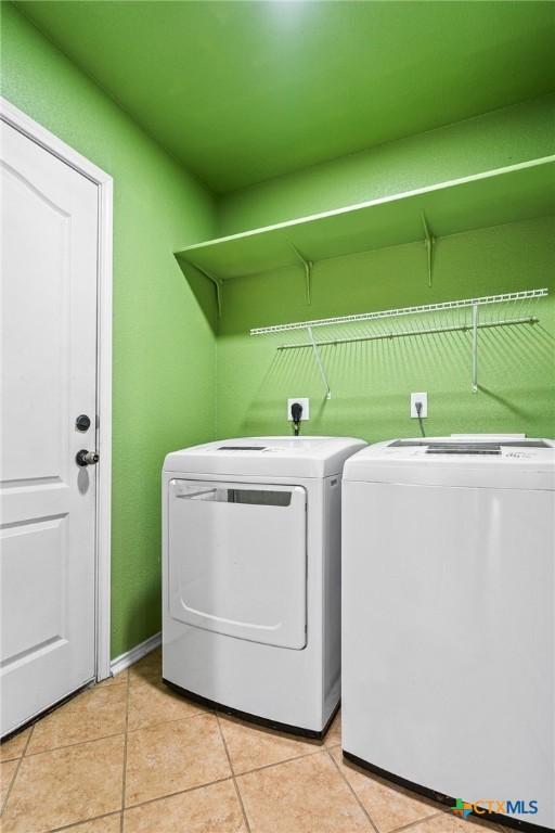 clothes washing area with light tile patterned floors and separate washer and dryer