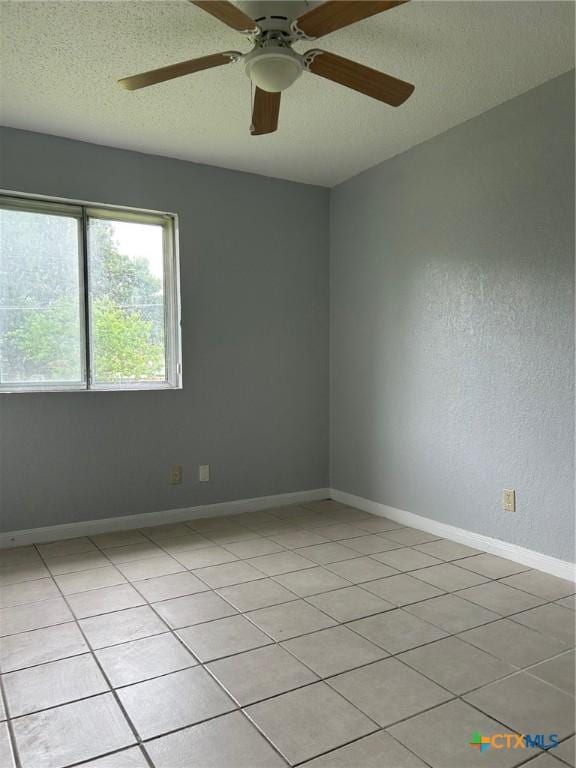 unfurnished room with light tile patterned floors, baseboards, a ceiling fan, and a textured ceiling
