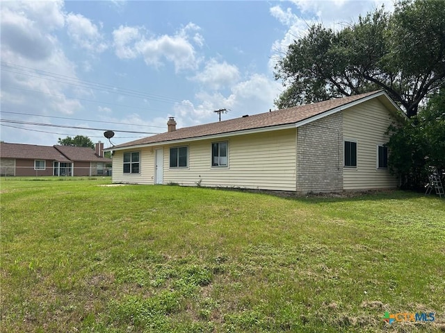 back of house with a chimney and a yard