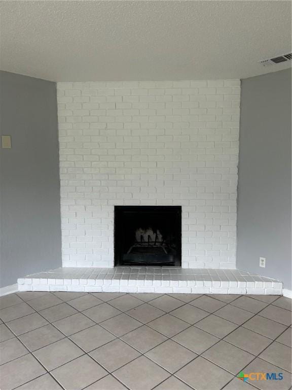 details with baseboards, a fireplace, a textured ceiling, and visible vents