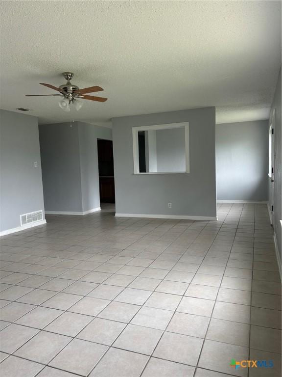 spare room with light tile patterned flooring, ceiling fan, a textured ceiling, baseboards, and visible vents
