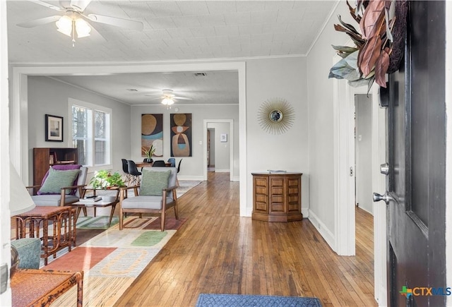 interior space with wood-type flooring, crown molding, baseboards, and ceiling fan