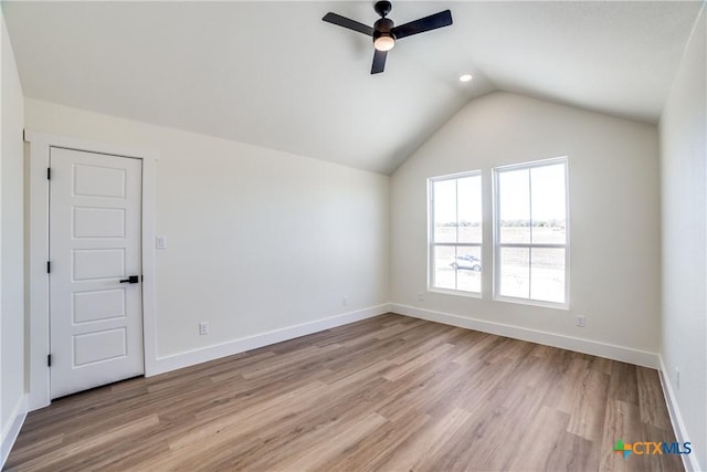 spare room with ceiling fan, lofted ceiling, and light hardwood / wood-style flooring