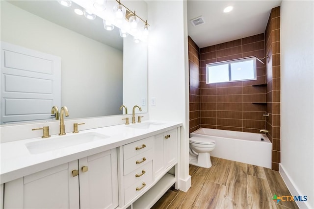 full bathroom featuring vanity, wood-type flooring, tiled shower / bath combo, and toilet