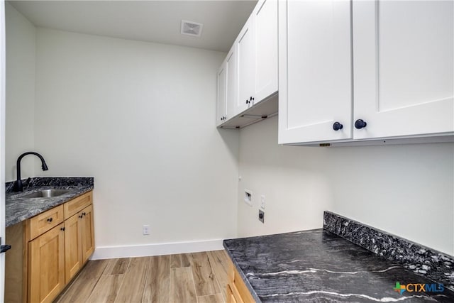 laundry room with hookup for an electric dryer, light hardwood / wood-style floors, cabinets, and sink