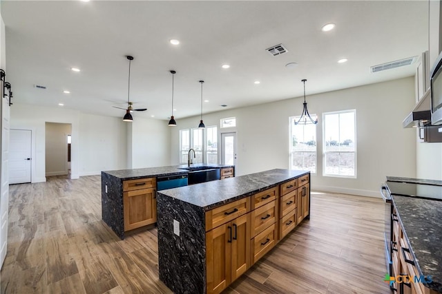 kitchen featuring sink, electric range, hardwood / wood-style floors, hanging light fixtures, and a large island