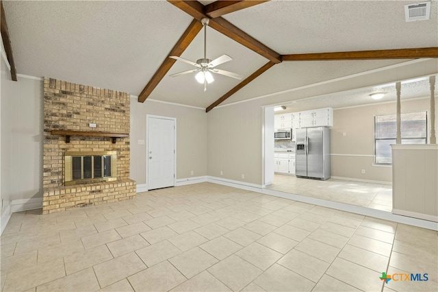 unfurnished living room featuring ceiling fan, a brick fireplace, lofted ceiling with beams, light tile patterned flooring, and a textured ceiling