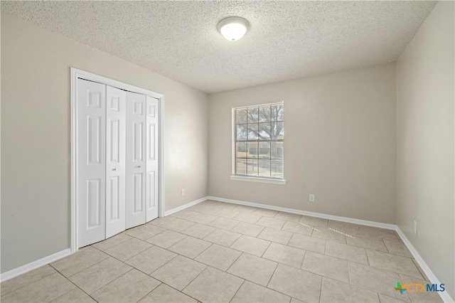 unfurnished bedroom featuring a textured ceiling, a closet, and light tile patterned flooring