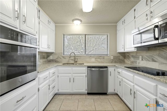 kitchen with light tile patterned floors, white cabinets, appliances with stainless steel finishes, and sink