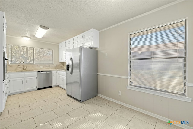 kitchen with appliances with stainless steel finishes, sink, white cabinetry, and ornamental molding