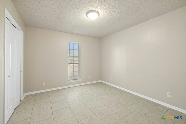 unfurnished bedroom with a textured ceiling, light tile patterned floors, and a closet