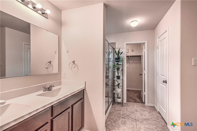 bathroom featuring walk in shower, vanity, a textured ceiling, and tile patterned floors