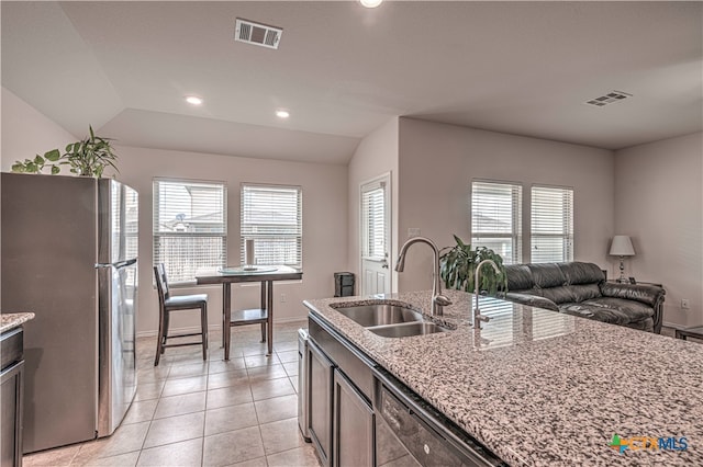 kitchen with stainless steel refrigerator, a healthy amount of sunlight, sink, and vaulted ceiling