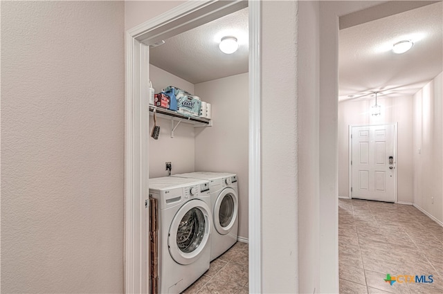 clothes washing area featuring independent washer and dryer, light tile patterned floors, and a textured ceiling