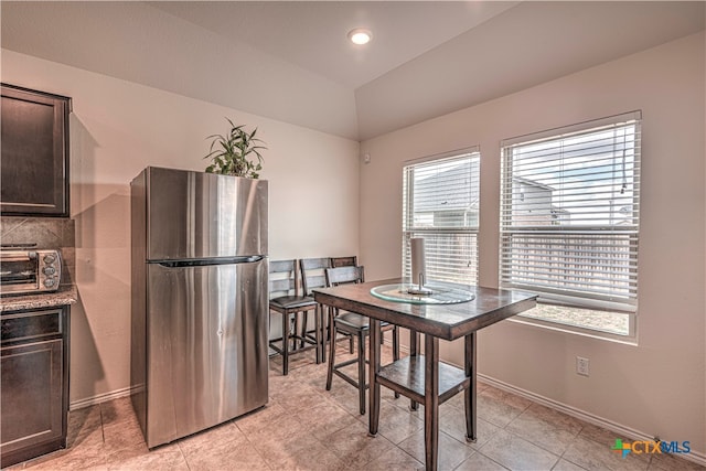 dining space featuring light tile patterned floors and vaulted ceiling