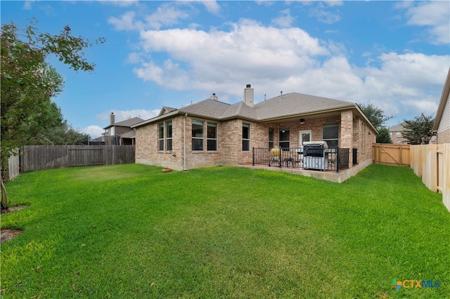 rear view of property with a lawn and a patio