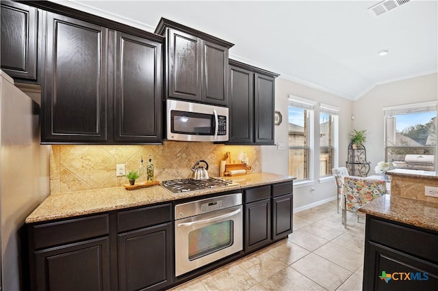 kitchen featuring vaulted ceiling, decorative backsplash, light tile patterned floors, light stone counters, and stainless steel appliances