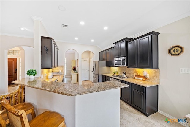 kitchen with backsplash, light stone countertops, kitchen peninsula, and stainless steel appliances