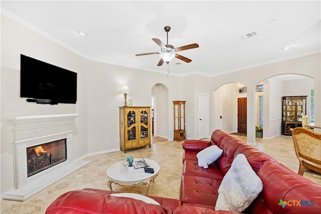 tiled living room with ceiling fan and crown molding