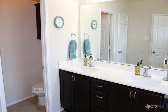 bathroom with toilet, vanity, and tile patterned floors