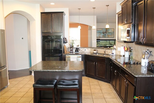 kitchen with sink, black appliances, kitchen peninsula, a breakfast bar area, and pendant lighting