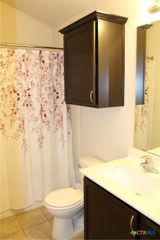 bathroom with toilet, vanity, and tile patterned flooring