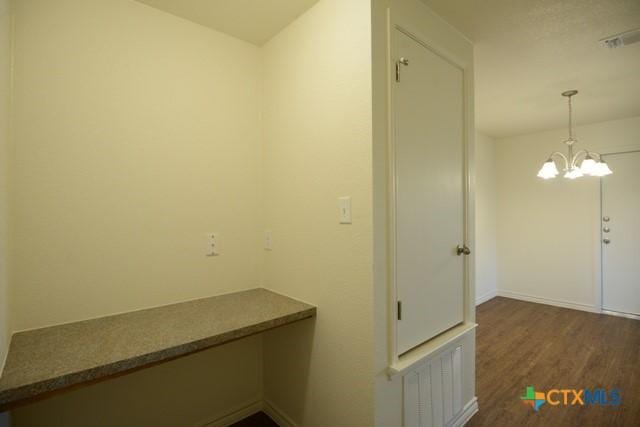 hallway with dark hardwood / wood-style floors and a notable chandelier