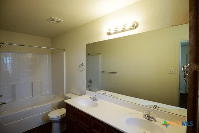 full bathroom featuring washtub / shower combination, vanity, and toilet