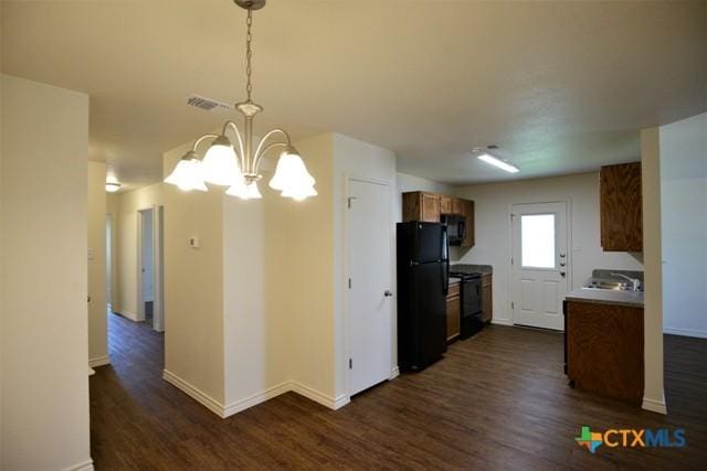 kitchen featuring pendant lighting, dark wood-type flooring, black appliances, and a notable chandelier