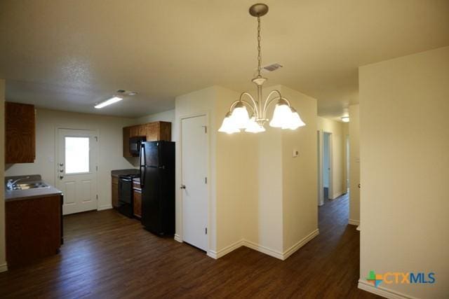 kitchen featuring black appliances, a notable chandelier, dark wood-type flooring, and hanging light fixtures