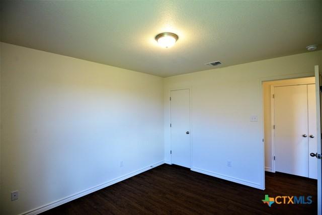 unfurnished bedroom with dark hardwood / wood-style flooring