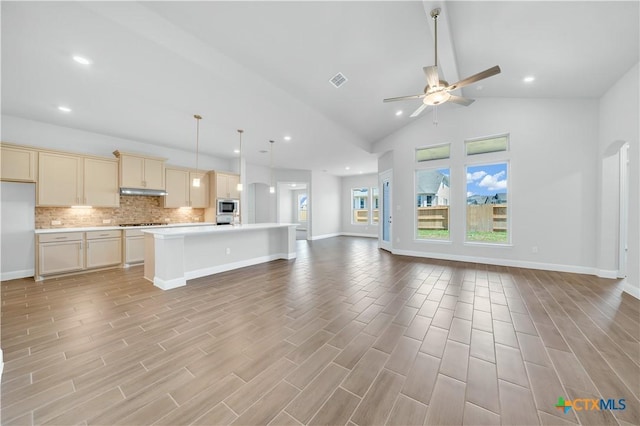 kitchen featuring ceiling fan, tasteful backsplash, open floor plan, and light countertops