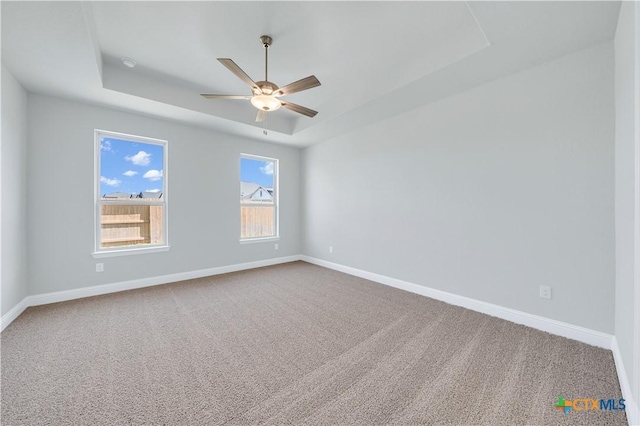 spare room featuring baseboards, a raised ceiling, carpet floors, and ceiling fan