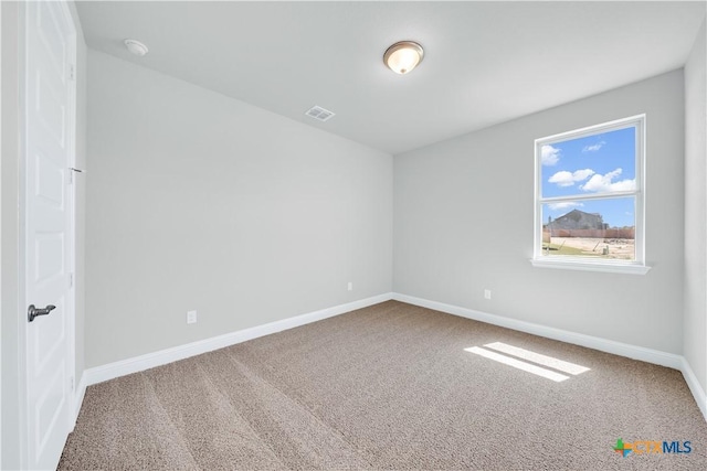 empty room with carpet, visible vents, and baseboards