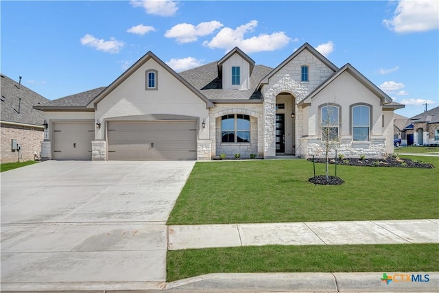 french country inspired facade with a shingled roof, a front lawn, a garage, stone siding, and driveway