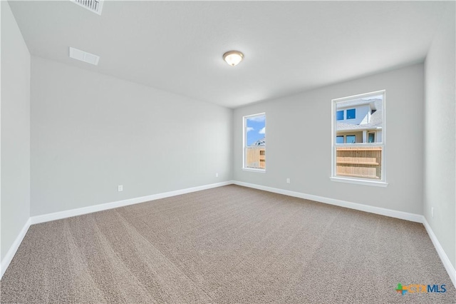 carpeted spare room featuring visible vents and baseboards