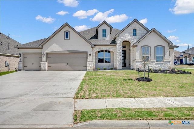 french country inspired facade with a front yard, an attached garage, stone siding, and concrete driveway