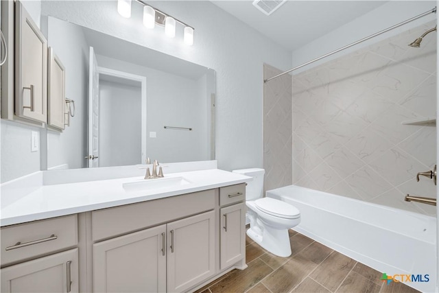 full bathroom with visible vents, tub / shower combination, wood tiled floor, toilet, and vanity