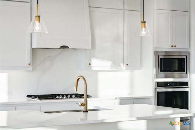 kitchen with tasteful backsplash, white cabinetry, hanging light fixtures, and stainless steel appliances