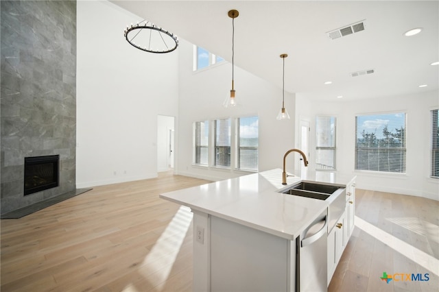 kitchen featuring plenty of natural light, hanging light fixtures, sink, and an island with sink